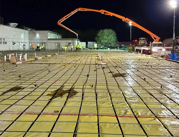 Concrete pour at night with boom pump and rebar grid.